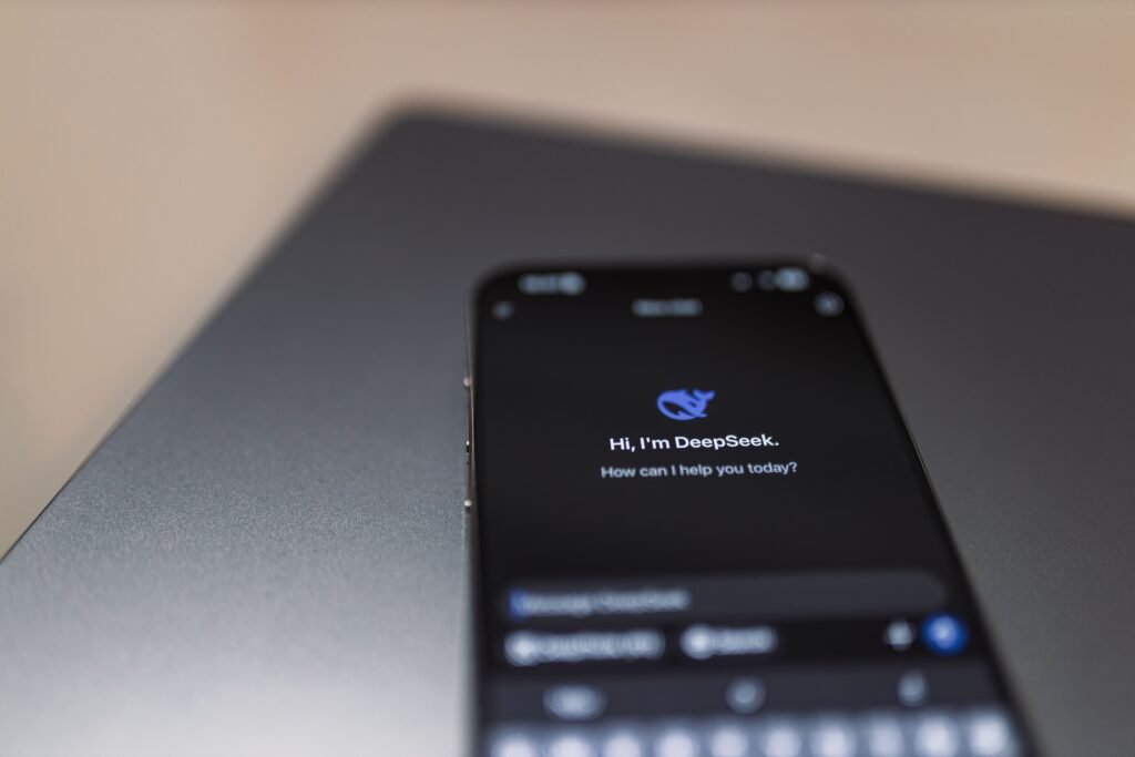 Close-up of a smartphone showing an AI assistant interface over a laptop, representing the Gemini app