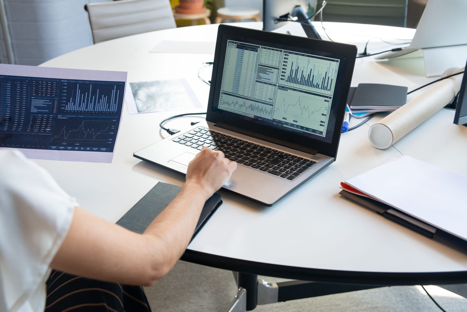 Person reviewing financial and performance charts on paper and laptop during a site audit